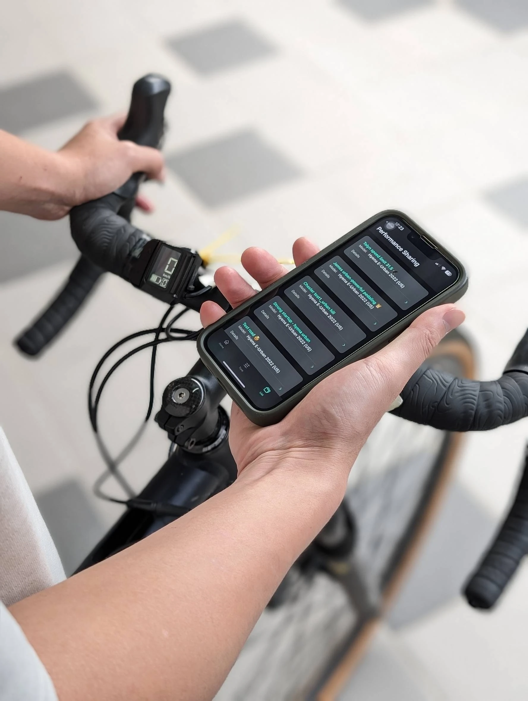 Tuner's Performance Sharing screen showing multiple riding configurations on a phone beside an e-bike handlebar.