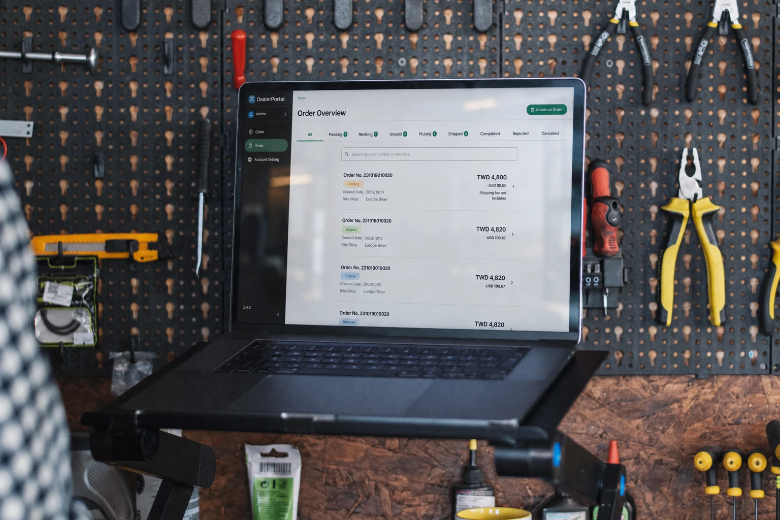 A laptop displaying the dealer portal in a bicycle workshop, with natural screen lighting and reflections.